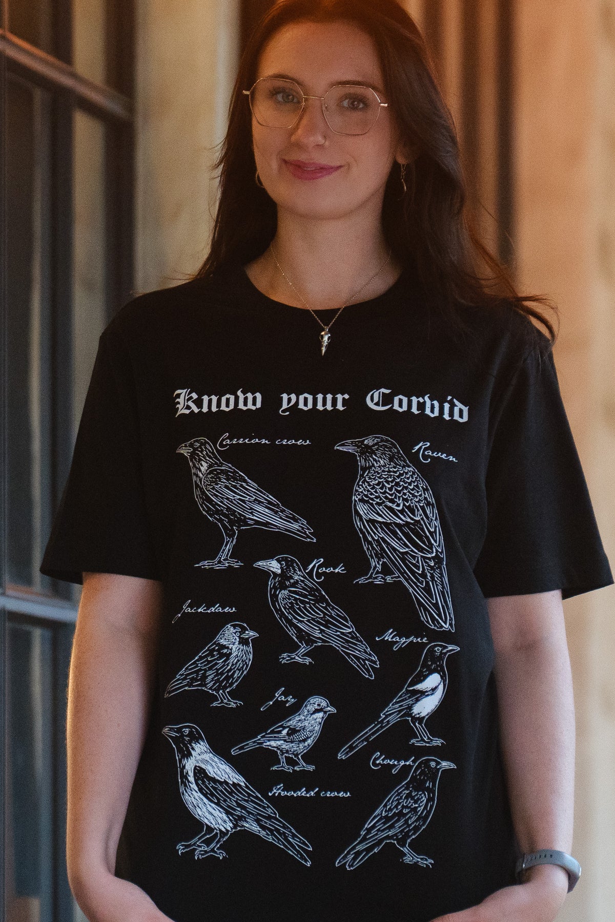 Black T-shirt printed with Abi’s white illustration of eight British Isles corvids: raven, carrion crow, hooded crow, rook, jackdaw, magpie, jay and chough.