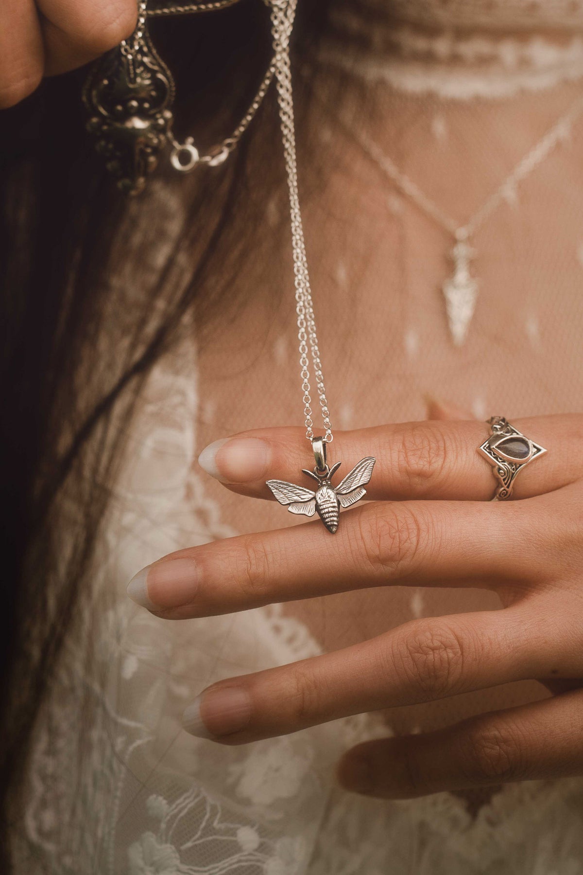 Woman holding a sterling-silver hawk moth pendant